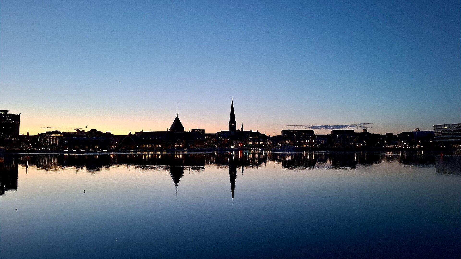 Night skyline of Aarhus with the cathedral spire reflected across the harbor