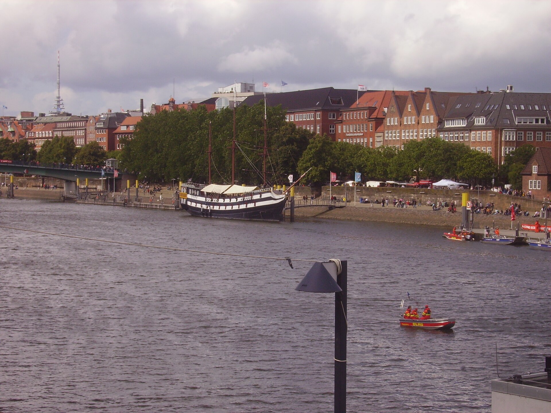 Wide view across the Weser in Bremen with waterfront buildings and a historic ship