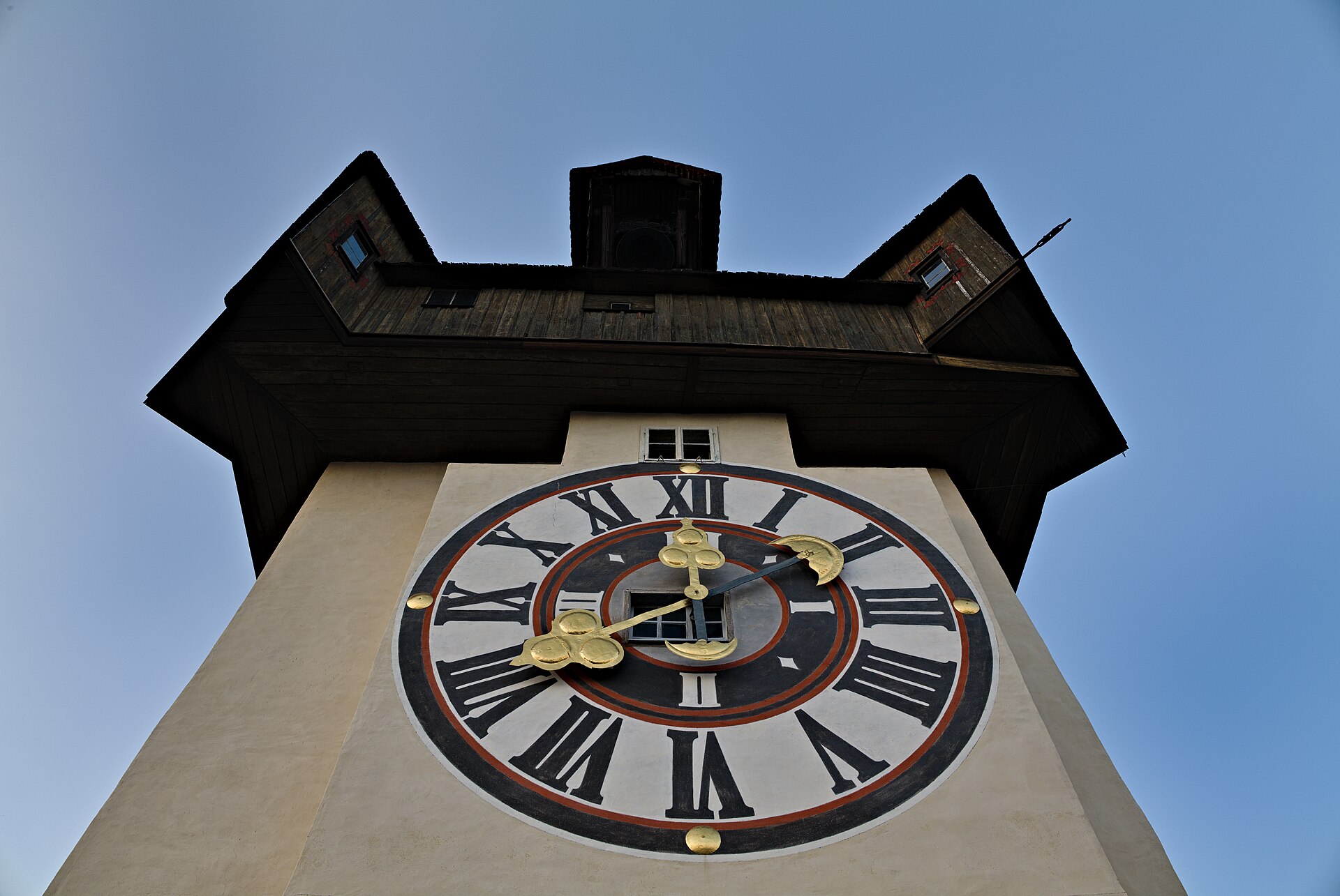 The clock tower on Graz's Schloßberg seen from below against a pale sky