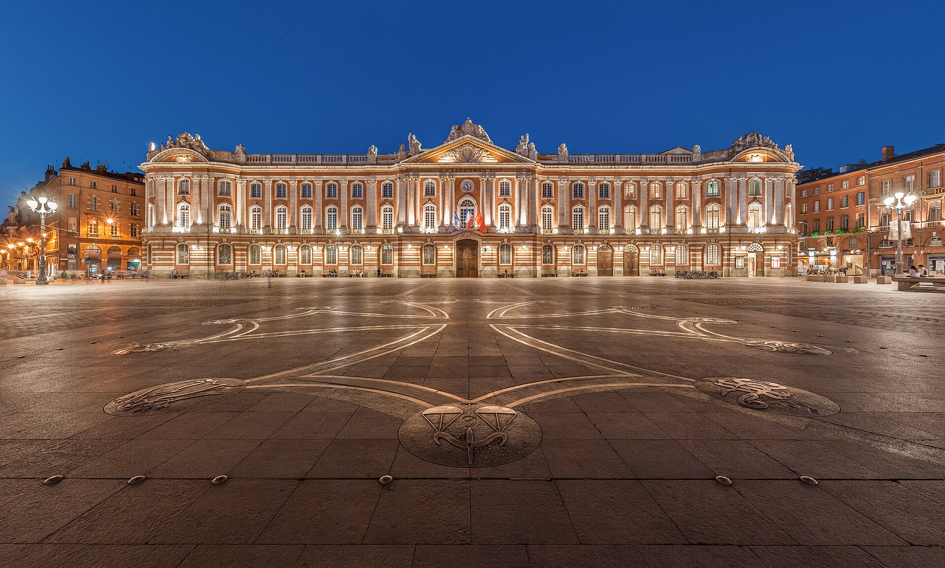 The Capitole building lit at night across the broad square in Toulouse