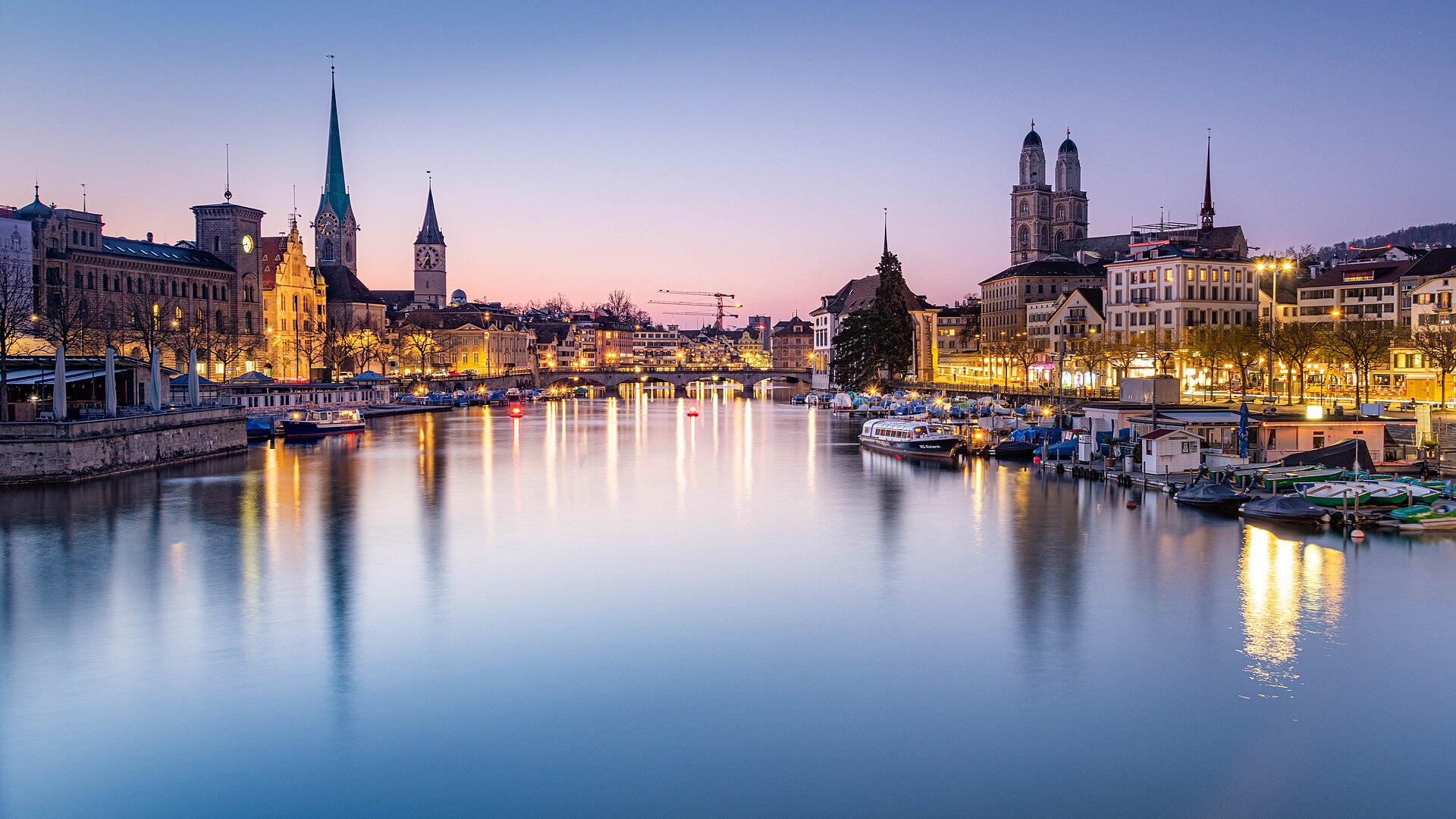 Blue-hour view across central Zurich and the Limmat